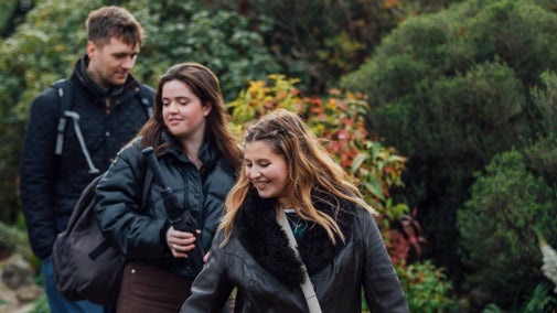3 visitors walk in a line exploring Emmetts Garden in autumn